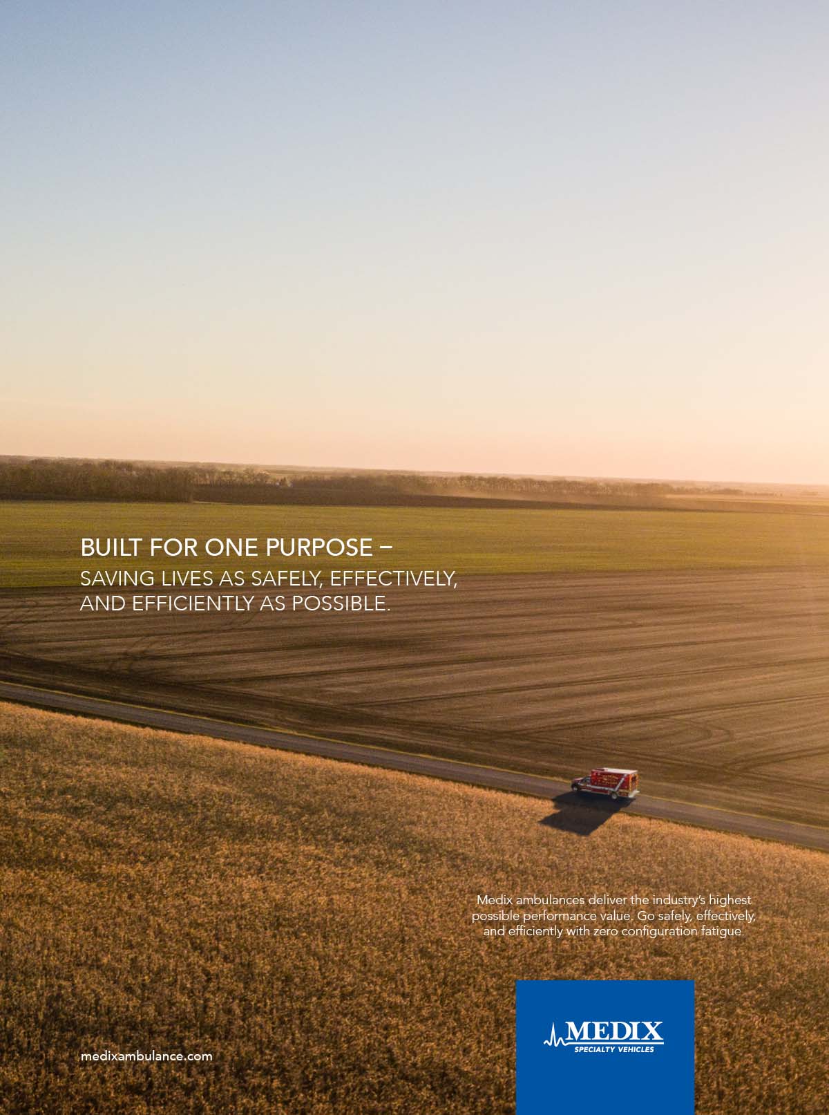 A Medix ambulance shown from far away drives down a thin road in the middle of vast farm fields on either side