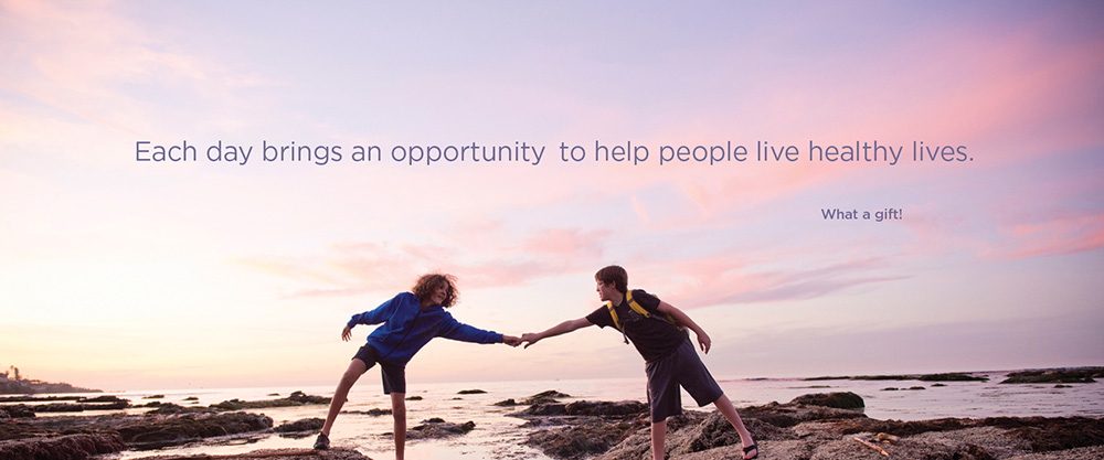 two kids walking on rock near water reach out an arm to help each other