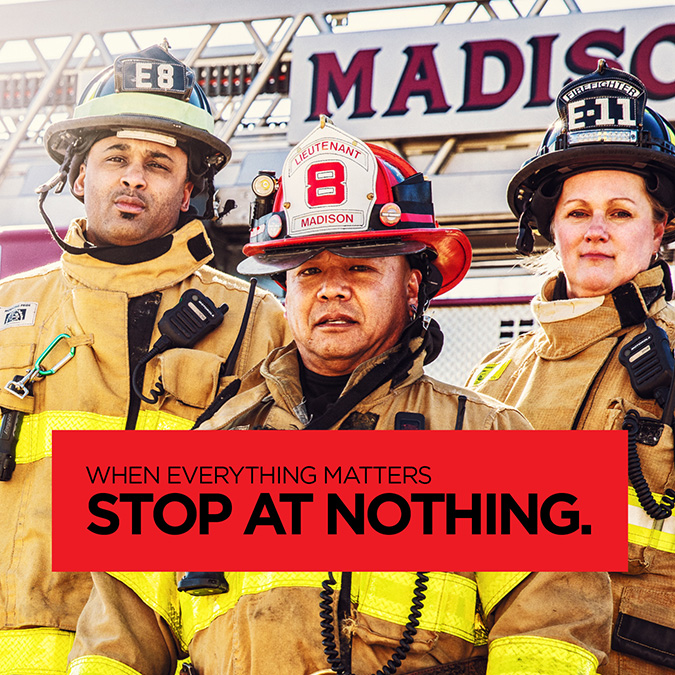 a group of three firefighters standing in front of a Pierce firetruck