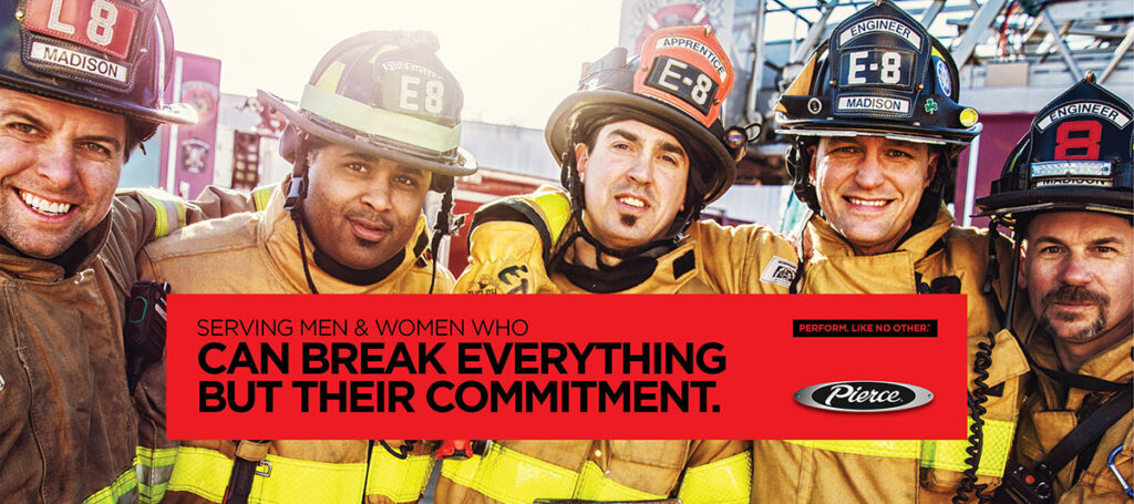 A group of smiling firefighters in their gear with Pierce logo