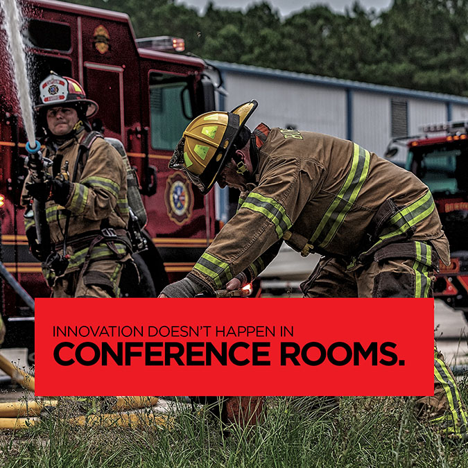 Pierce Manufacturing photo of two firefighters, one operating a fire hose, the other a fire hydrant, standing in front of a firetruck