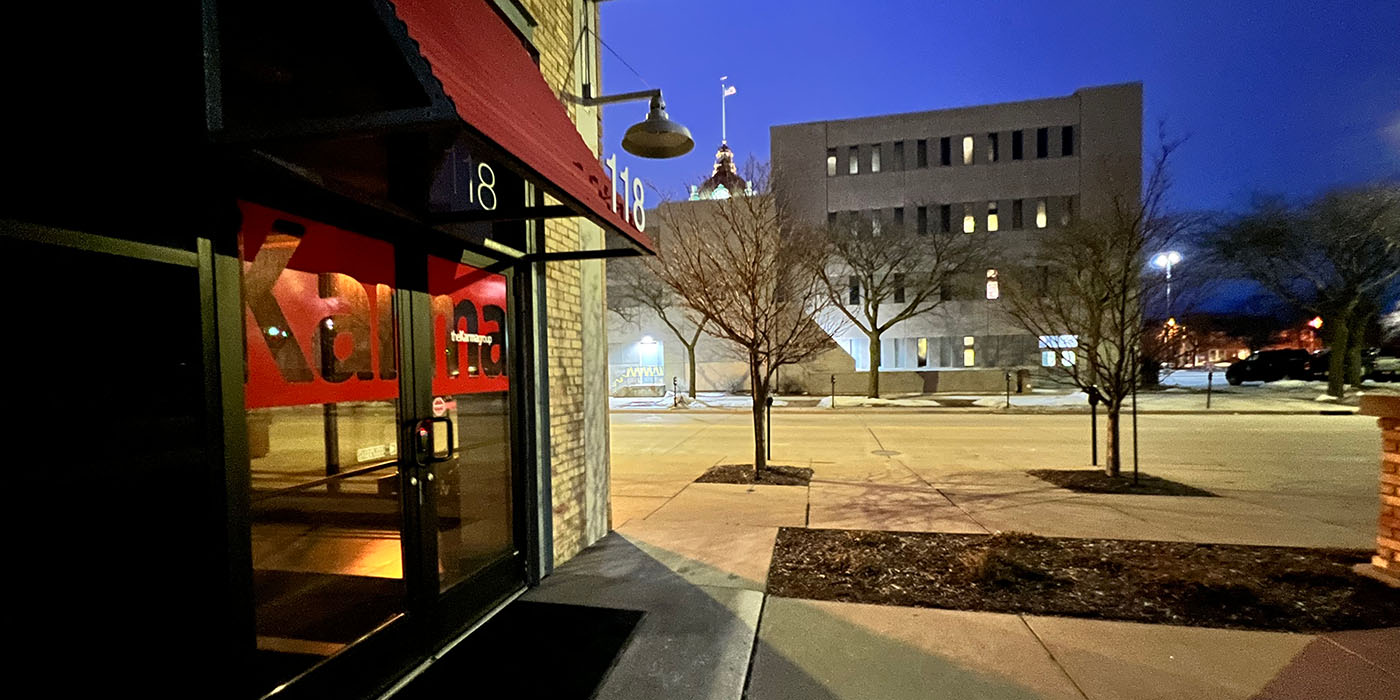 Exterior photo in the evening of the front door of The Karma Group offices at 118 South Adams, Green Bay